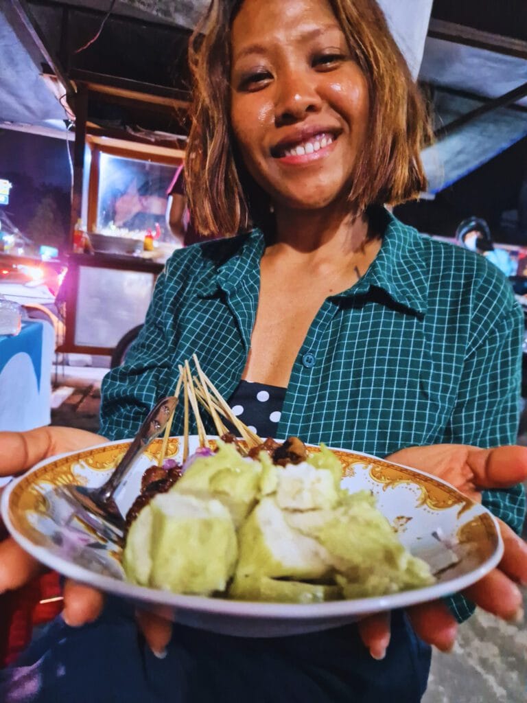 Smiling proudly with a delicious plate of chicken satay