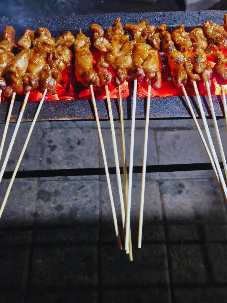 Smiling proudly with a delicious plate of chicken satay